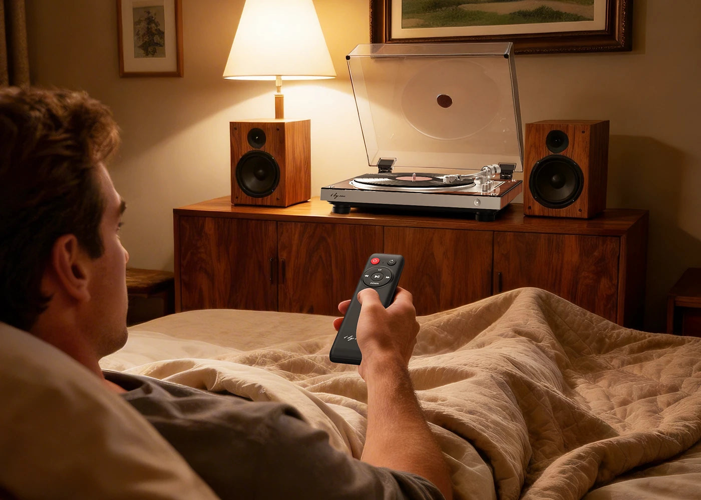 A man uses a remote from bed to operate a fully automatic turntable to enjoy effortless wireless audio control. 