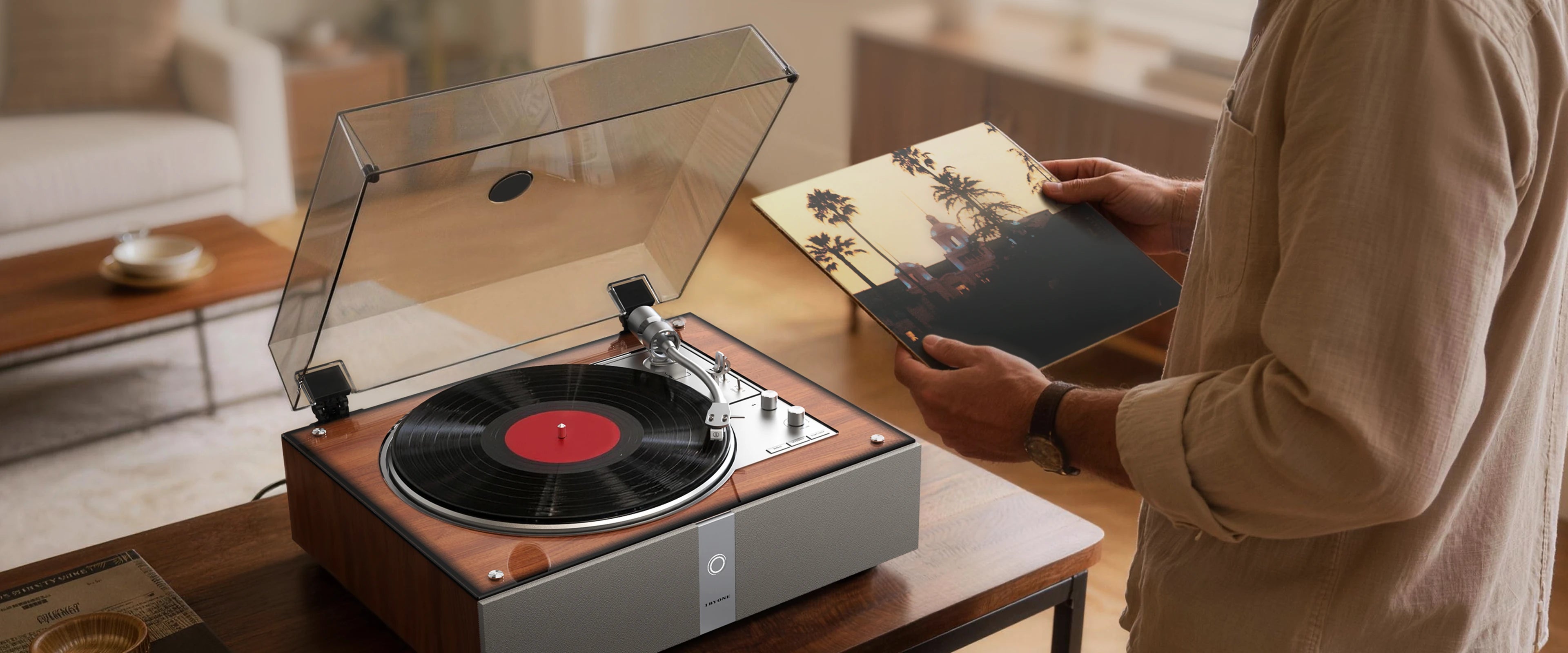 Person holding a vinyl album next to the vintage record player.