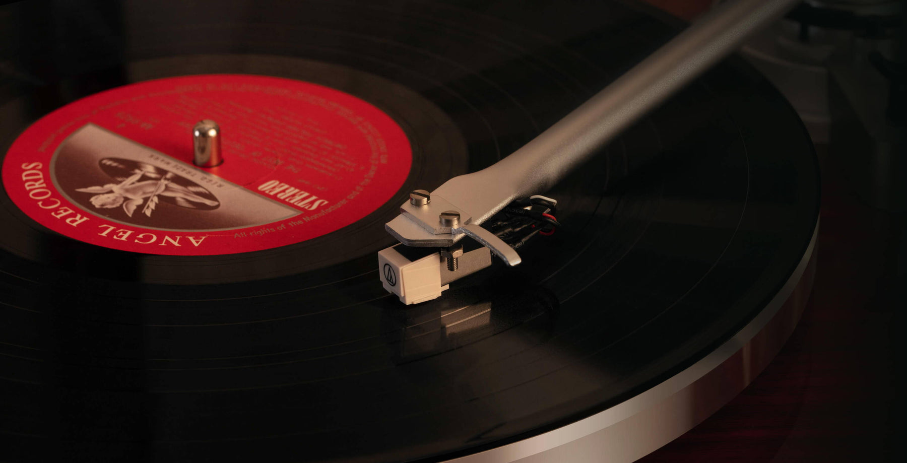  Close-up of a turntable cartridge and stylus tracking a spinning record with a red label