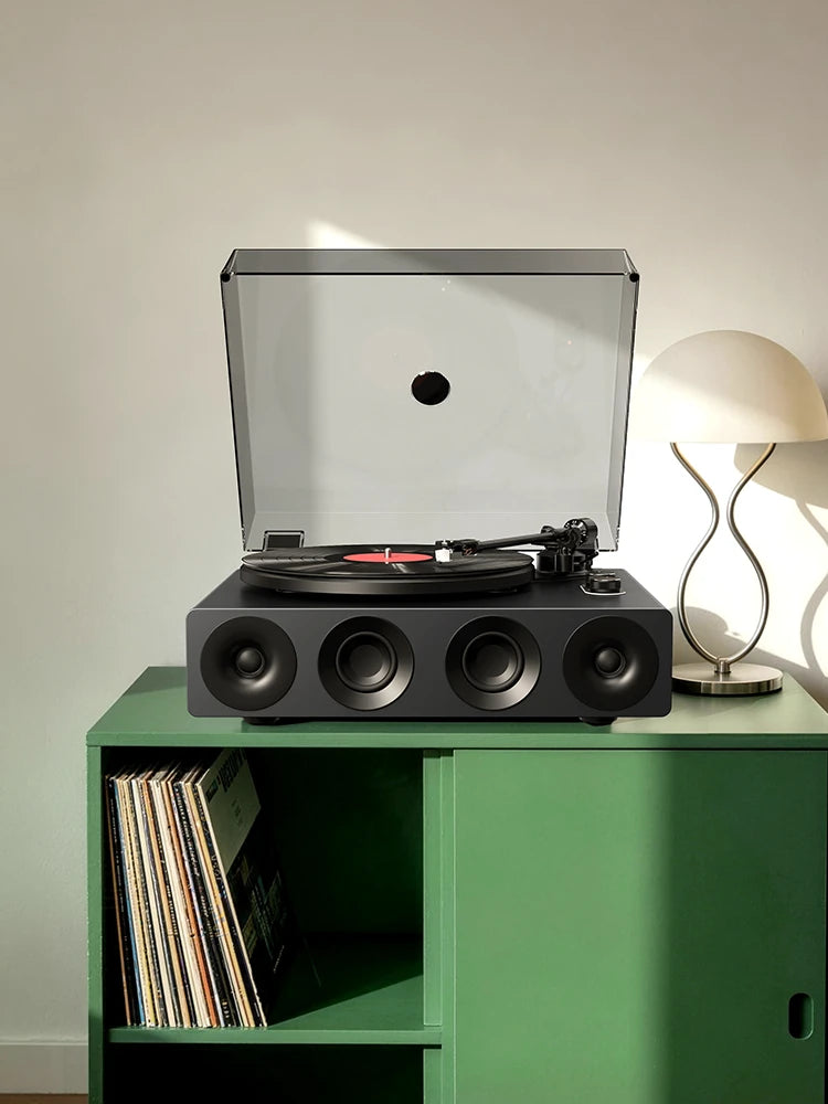 Grey all-in-one bluetooth record player on a green vinyl stand with vinyl storage.