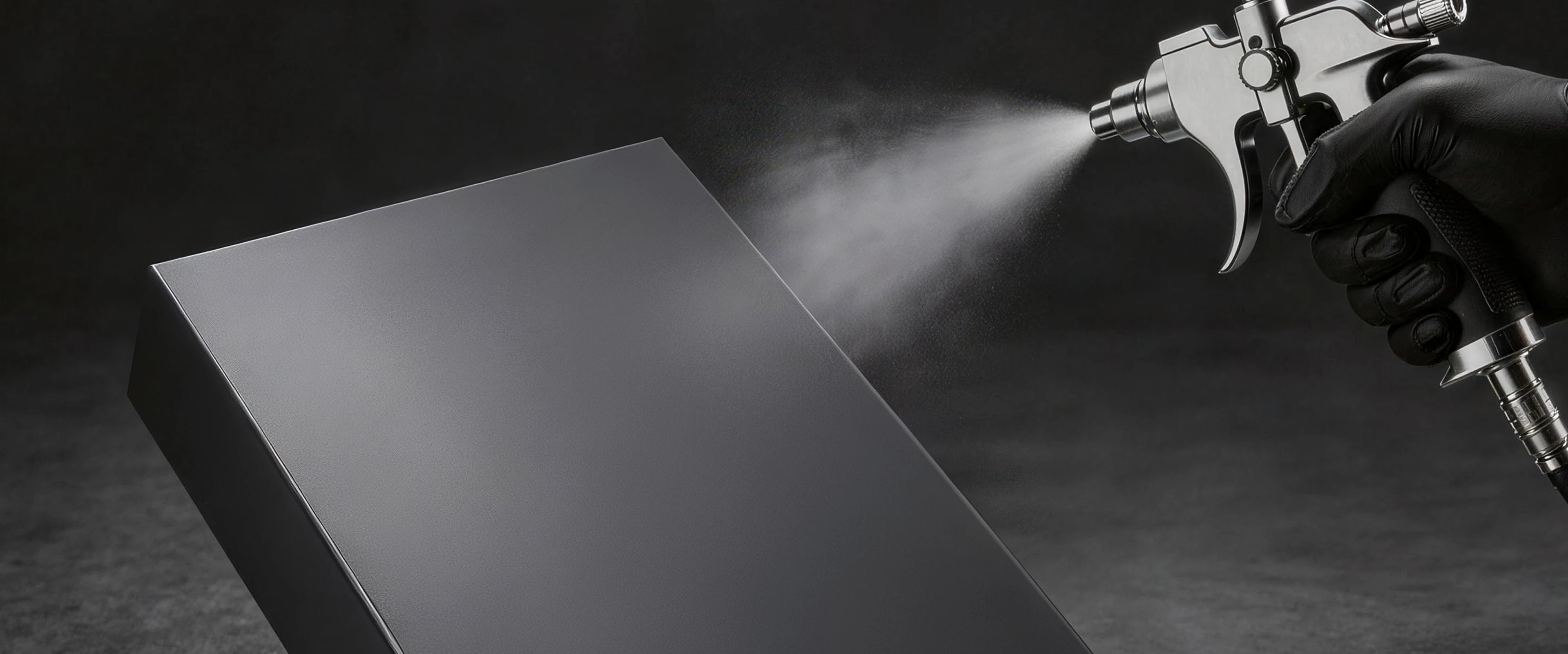 Spray-applying a smooth matte grey finish to an all-in-one record player base in a studio