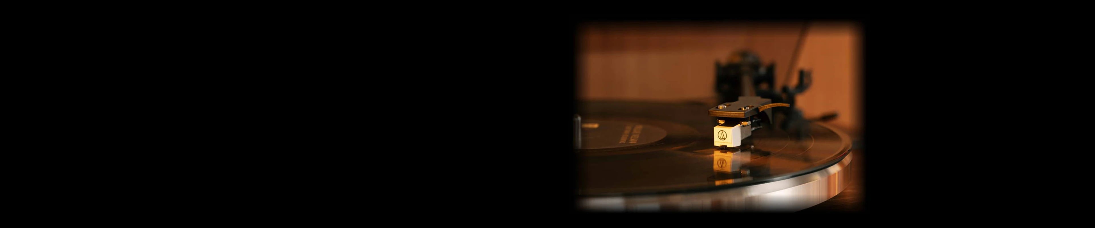 Close-up of a premium Audio-Technica phono cartridge tracing a spinning vinyl.